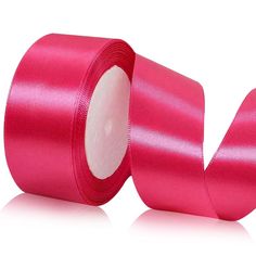 a roll of pink satin ribbon on a white background, with one roll in the foreground