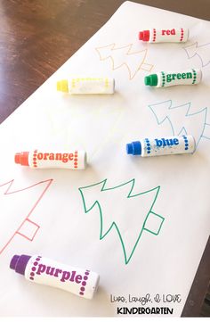 four crayon markers sitting on top of a white paper with orange, green and blue writing