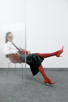 a woman sitting in a chair with her legs spread out and wearing red tights