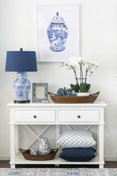 a blue and white vase sitting on top of a table next to a basket filled with flowers