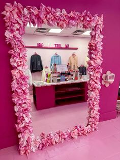 a mirror with pink flowers on it in a room filled with clothes and other items