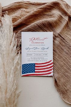 an american flag is on the back of a wedding card and some feathers are laying next to it