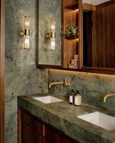 a bathroom with marble counter tops and two sinks in front of a mirror that has lights on it