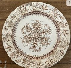 two plates sitting on top of a wooden table covered in brown and white floral designs