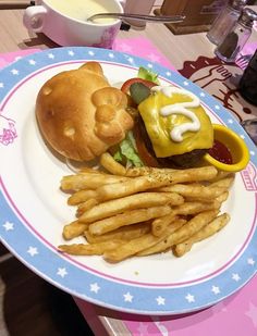 a hamburger and french fries on a blue and white plate with pink border around it