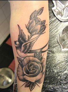 a black and white photo of a rose with two birds on it's arm