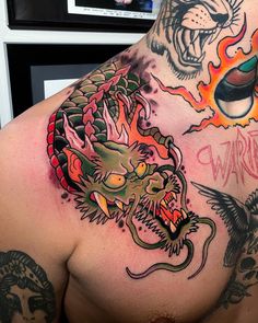 a man with tattoos on his chest and arm is showing off his dragon tattoo design