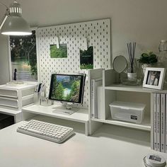 a white desk with a computer monitor and keyboard on top of it next to two bookshelves