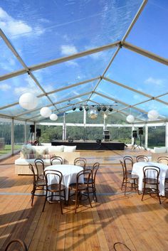 an outdoor venue with tables and chairs set up for a wedding or party under a clear roof