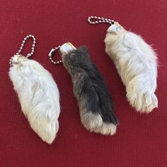 three furry animal keychains on a red surface with a chain attached to them