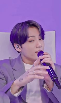 the man is holding a microphone in his hand and wearing a purple suit with white shirt