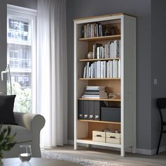 a living room filled with furniture and a book shelf in front of a large window