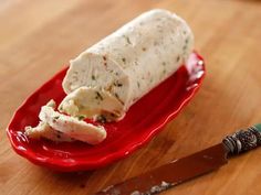 a red plate topped with food next to a knife on top of a wooden table