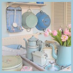 a kitchen counter with pots and pans hanging from the wall, flowers in a vase