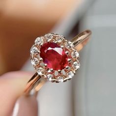 a close up of a person holding a ring with a red stone