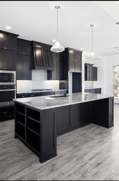 a large kitchen with black cabinets and marble counter tops