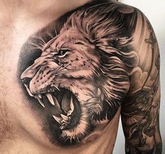 a man's chest with a lion tattoo on it and an eagle in the background