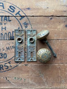 two antique door knobs on top of a wooden wall