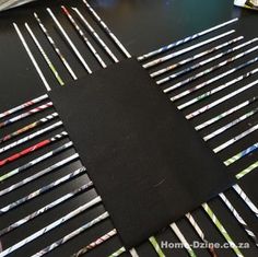 a bunch of pencils that are on top of a black paper sheet and some scissors in the background