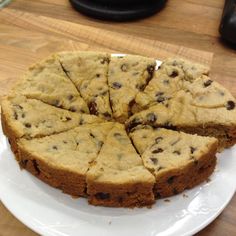 a cake sitting on top of a white plate covered in chocolate chip cheesecake slices