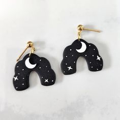 pair of black and white elephant shaped earrings with stars, moon and crescent design on them