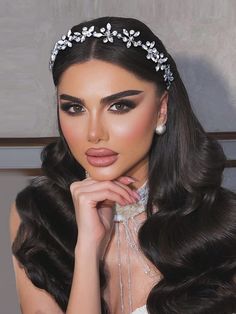 a woman with long dark hair wearing a tiara and pearls on it's head