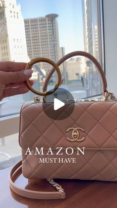 a handbag is being held up on a table in front of a large window