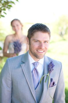 a man in a gray suit and tie standing next to a woman wearing a white dress