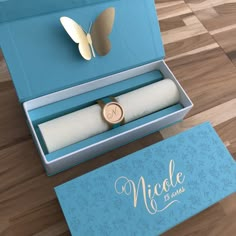 a blue box with a ring inside and a butterfly on the lid that says nicole de mare