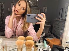 a woman taking a selfie in front of makeup brushes