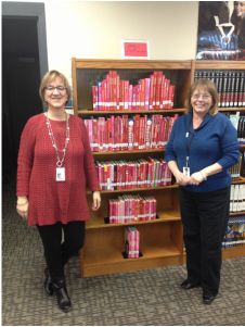 two women standing next to each other in front of a book shelf filled with books