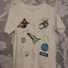 a white t - shirt with space patches on it