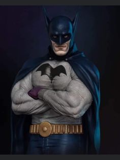 the batman statue is posed with his hands on his chest and arms crossed, in front of a dark background