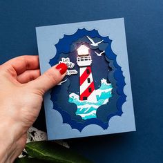 a hand holding a piece of paper with a lighthouse on it