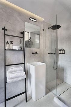 a bathroom with a stand up shower and white towels on the shelf next to it