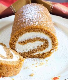 there is a roll on the plate with powdered sugar and icing around it