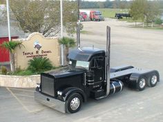 a black semi truck parked in front of a sign for temple r daniels motor sales