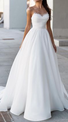 a woman in a white wedding dress standing on the sidewalk