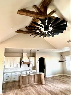 an open kitchen and dining room with wood beams on the ceiling, white cabinets and wooden flooring