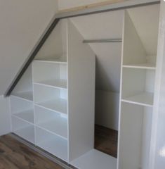 an empty room with white shelves and wooden floors