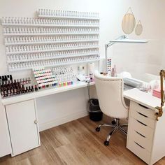 a white desk topped with lots of bottles of nail polish next to a wall mounted shelf