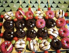 there are many donuts with eyes and noses on the tray, all decorated in different colors