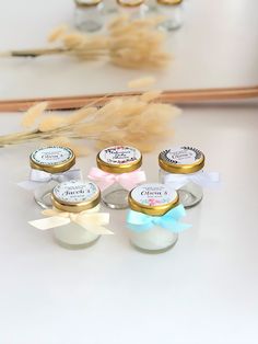 four small jars with labels on them sitting next to some feathers