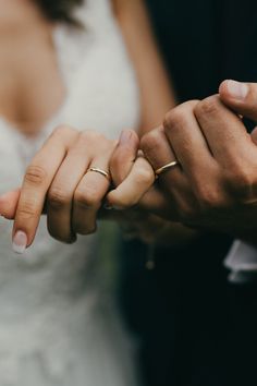 the bride and groom are holding hands with their wedding rings on their fingers as they hold each other's hand