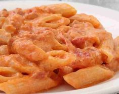 a white plate topped with pasta covered in meat and cheese sauce on top of a wooden table