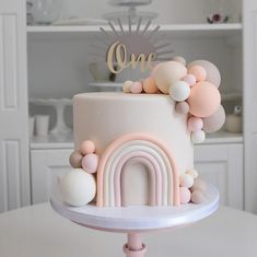 there is a white cake with pink and gold decorations on it, sitting on top of a table