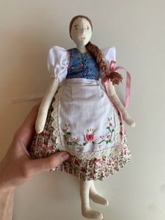 a hand holding a small doll in a dress