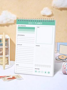 the daily planner is sitting next to some pens and magnets on a white table