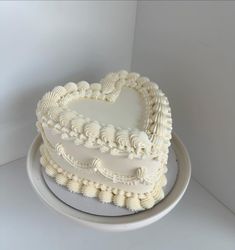 a white heart shaped cake sitting on top of a plate