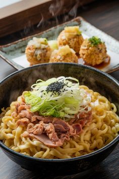 a bowl filled with noodles and meat on top of a wooden table